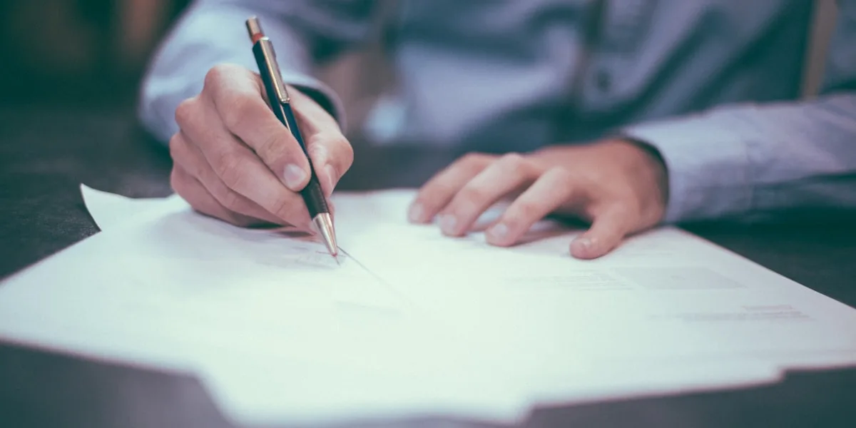 Mão assinando um documento para protocolar o recurso
